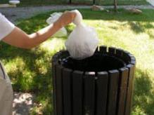 person putting tied up bag into the trash