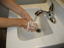 person washes hands with soap and water