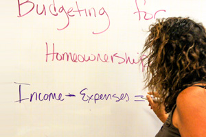Woman writing on white board about home ownership