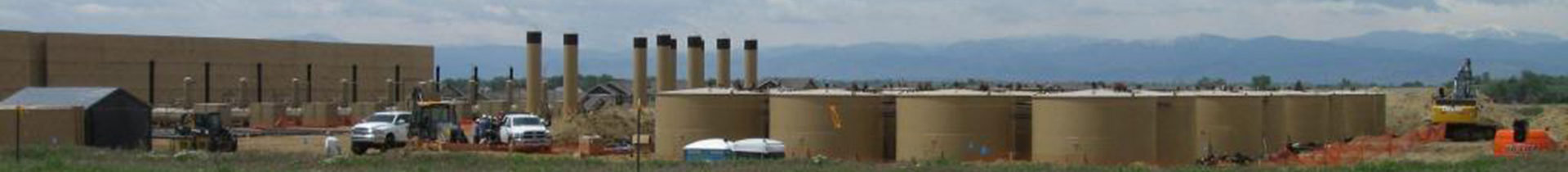 View of large oil and gas development facility with mountains in background