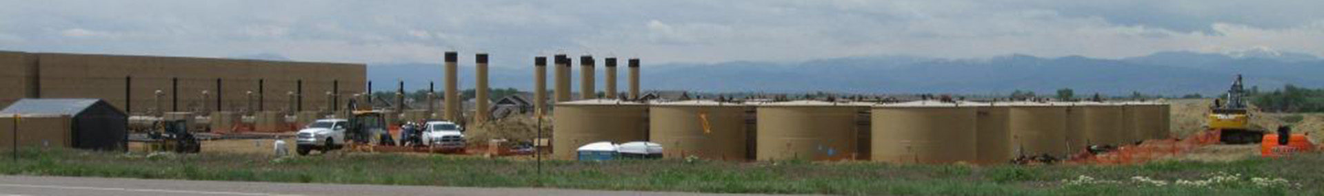 View of large oil and gas development facility with mountains in background
