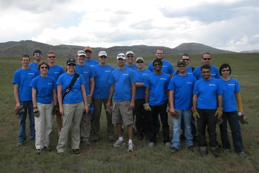 People gathered at the base of a mountain wearing matching blue shirts