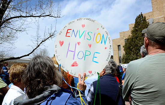 Local resident holds sign that says, "Envision Hope"