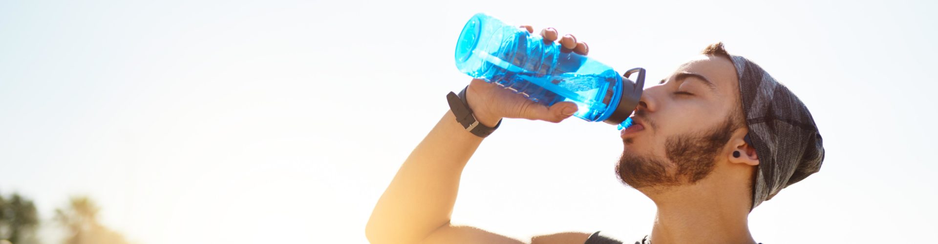 Shot of a sporty young man drinking water while exercising outdoors