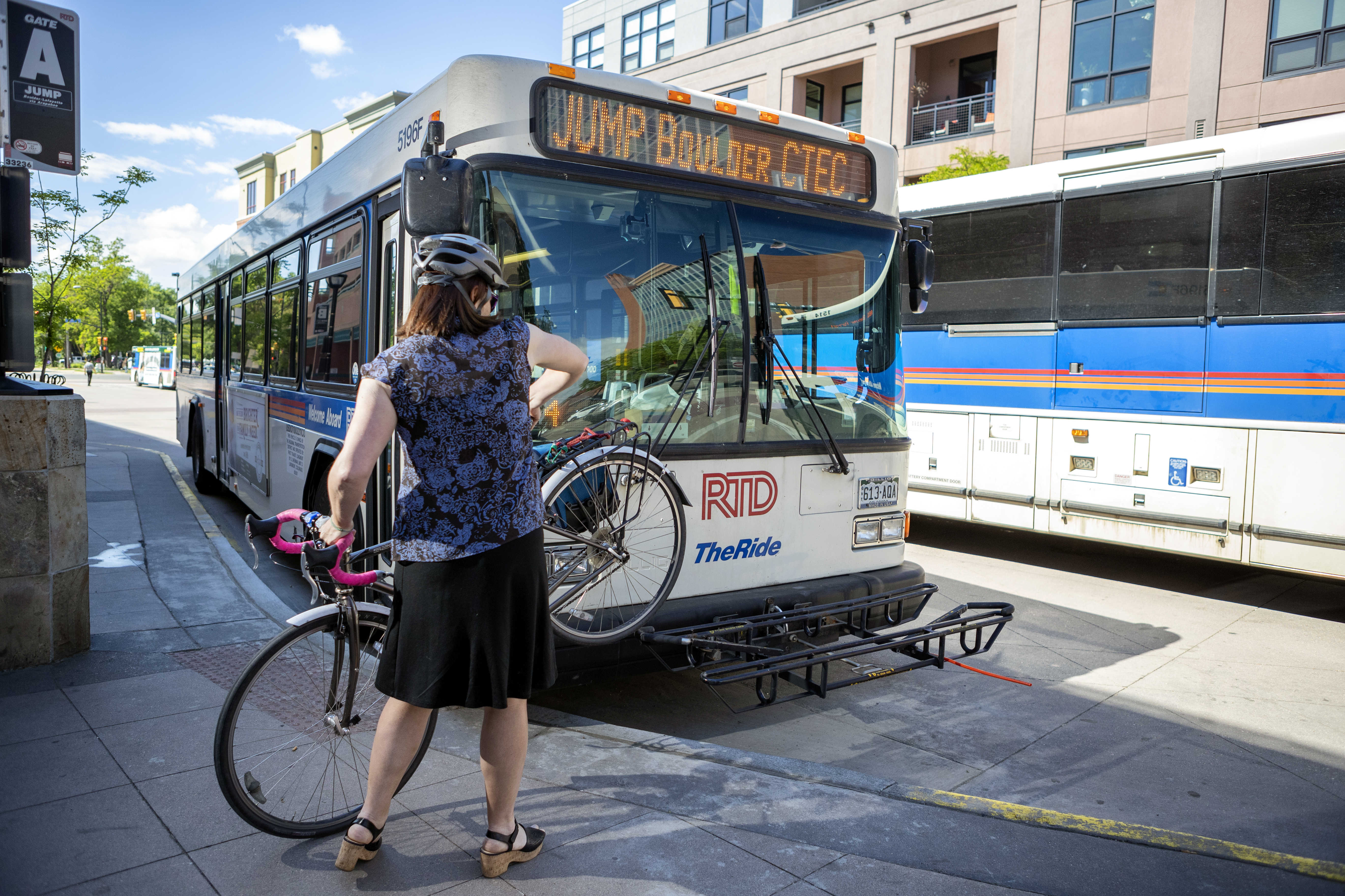 Boulder resident lifts bicycle on to bike rack on the front of local bus
