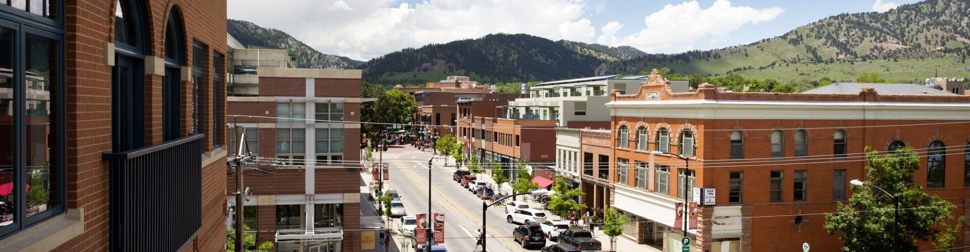 Aerial shot of Pearl Street in Downtown Boulder, featuring red brick buildings and the foothills in the background
