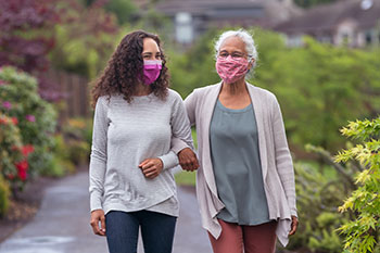 Senior woman and her adult daughter enjoying the outdoors with masks on