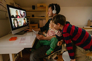 Photo of a man working from home, with his sons as a company, having a video conference call