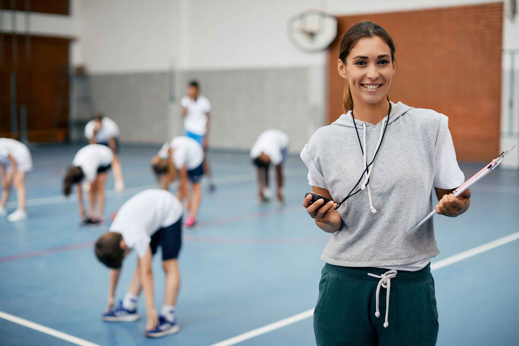 Portrait of happy female physical education teacher at school gym.
