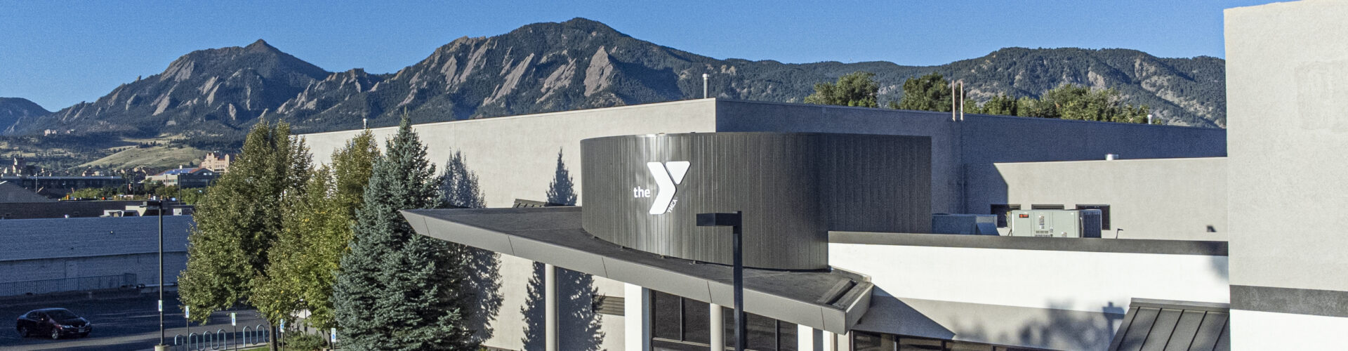 Photo of the Boulder YMCA building with the front range in the background