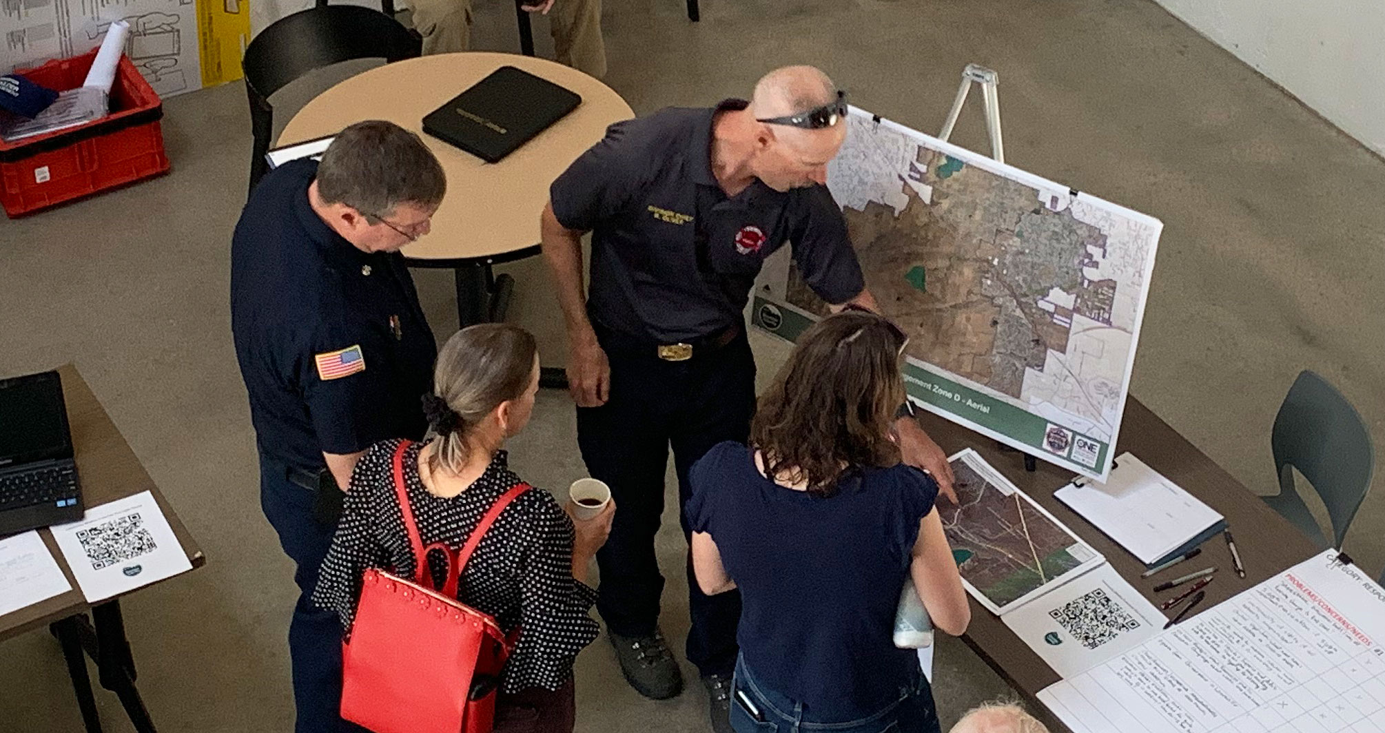 Community Members attending a Wildfire Mitigation meeting, looking at maps and discussing with firemen.