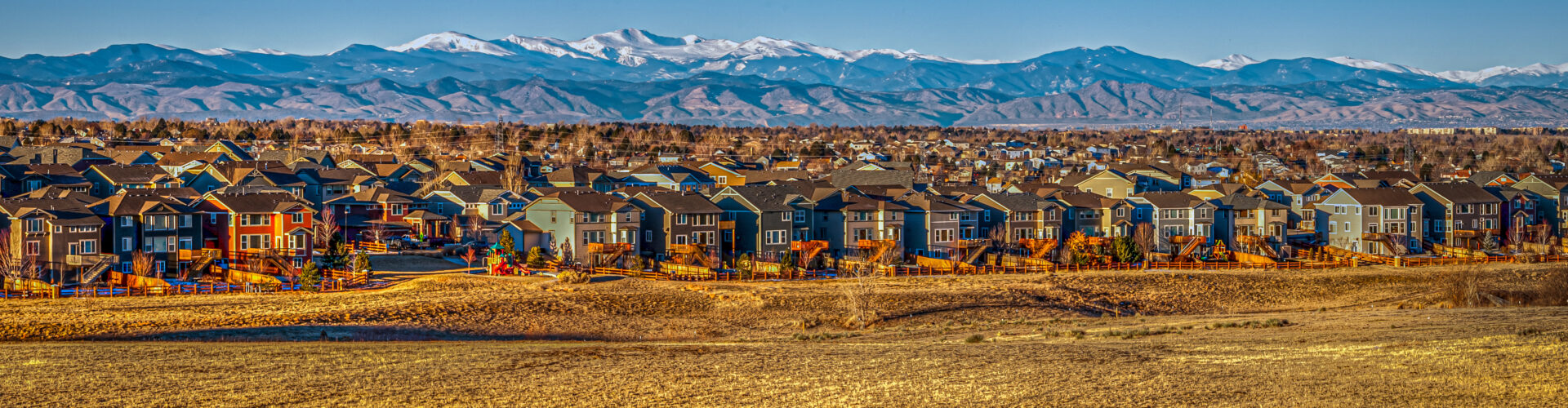 Lots of houses in residential neighborhood with the Rocky Mountains in the background.