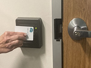 Hand holding a Boulder County Clerk and Recorder badge scanning into a secure door.