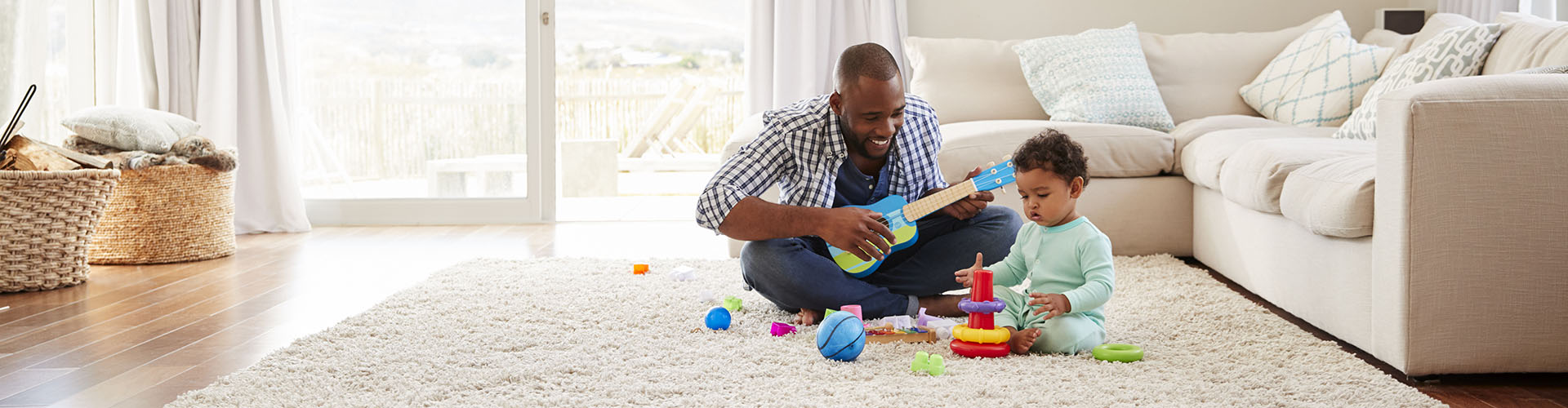 Black father playing with toddler on the living room floor