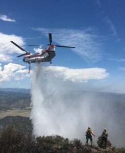 Helicopter dropping water on wildland fire
