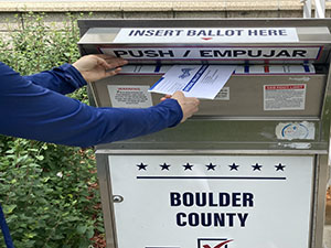 Hand dropping ballot into drop box.