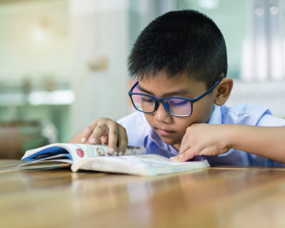 Young boy reading a book at a table