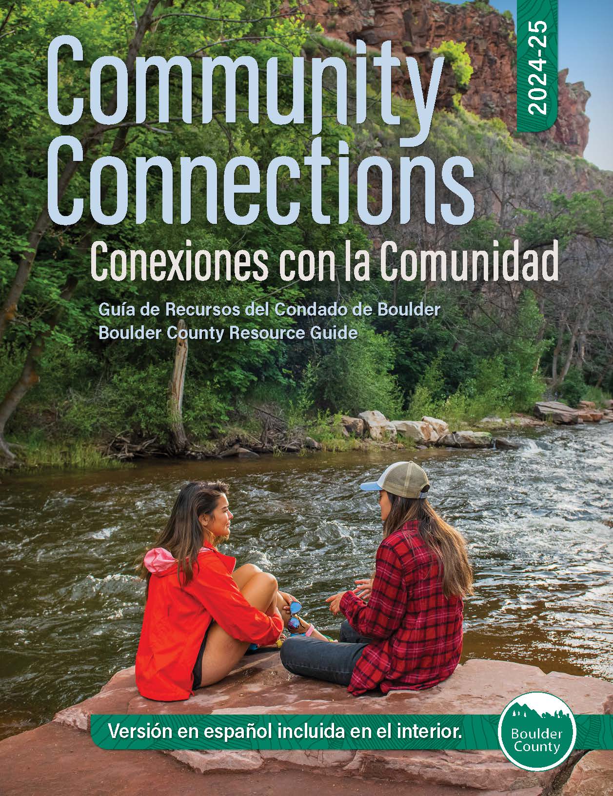 Community Connections Resource Guide cover. Two ladies sitting on a rock by a creek with mountain backdrop.