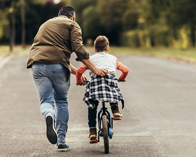 Dad helping son learn to ride a bike