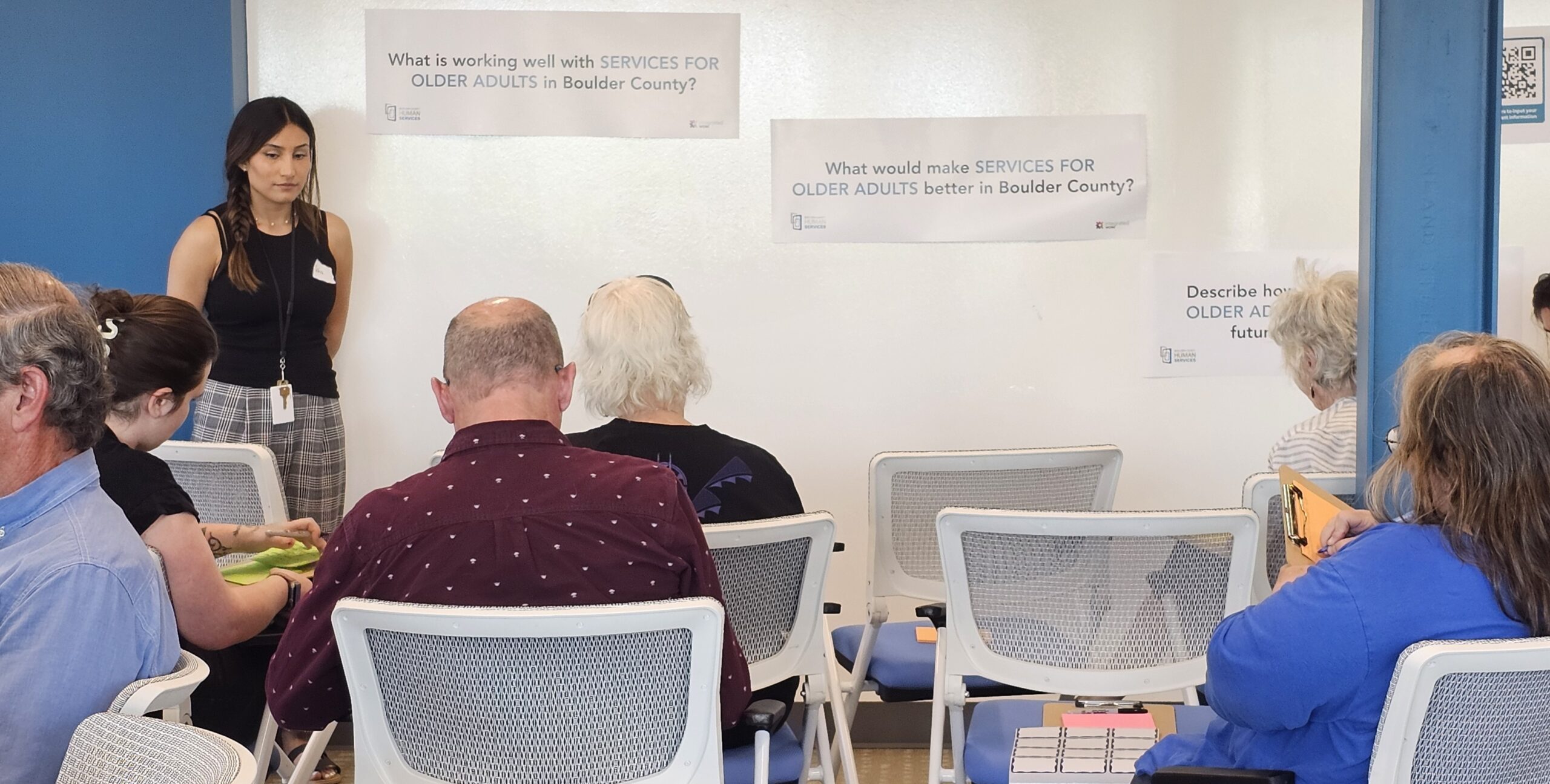 Image of community members sitting in front of a white board talking about human services and what is needed to improve them.