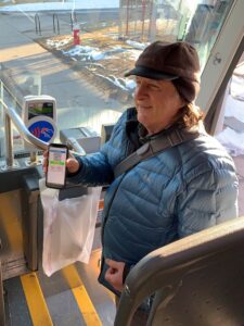 Older adult boarding bus using smartphone to show bus ticket.