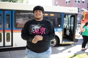 Young Adult smiling in front of an RTD bus.