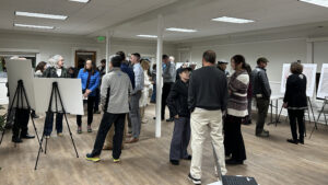 Bikeway Project 119 meeting participants in a room looking at images of the bikeway project plans and talking.