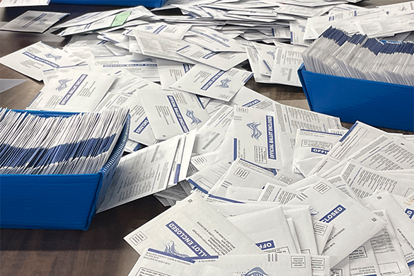 A pile of ballots is arrayed on a table.