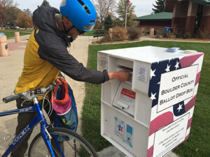 Man on bicycle dropping of his ballot at a 24-hour ballot drop box