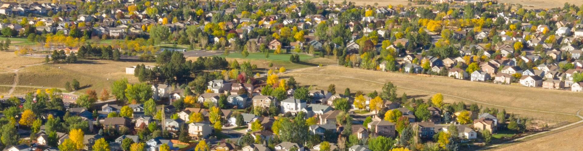 An arial view of neighborhood Housing surrounded by trees in fall color.