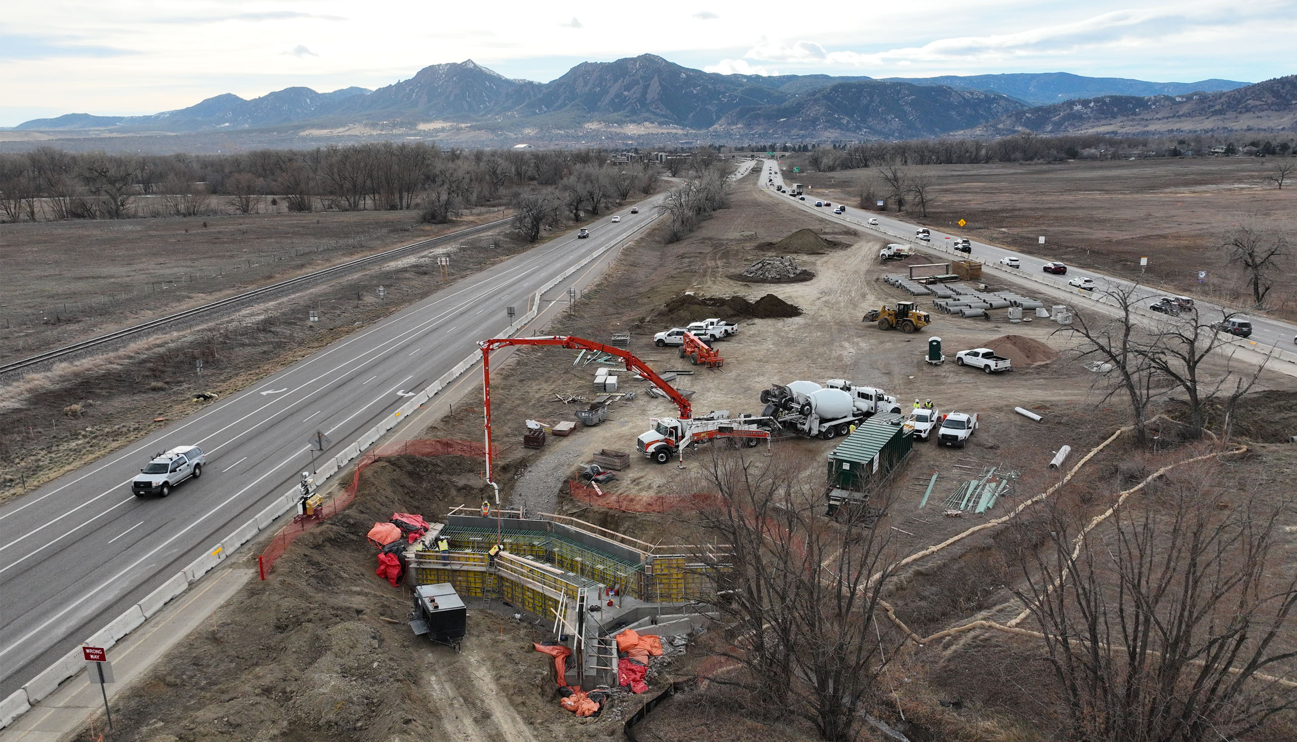 Construction in the median of CO 119 to extend culvert over ditch to create a bridge for the new bikeway. Flation mountains of Boulder in the background.