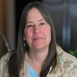 Headshot of a Annette Treufeldt-Frank with long hair , smiling at the camera