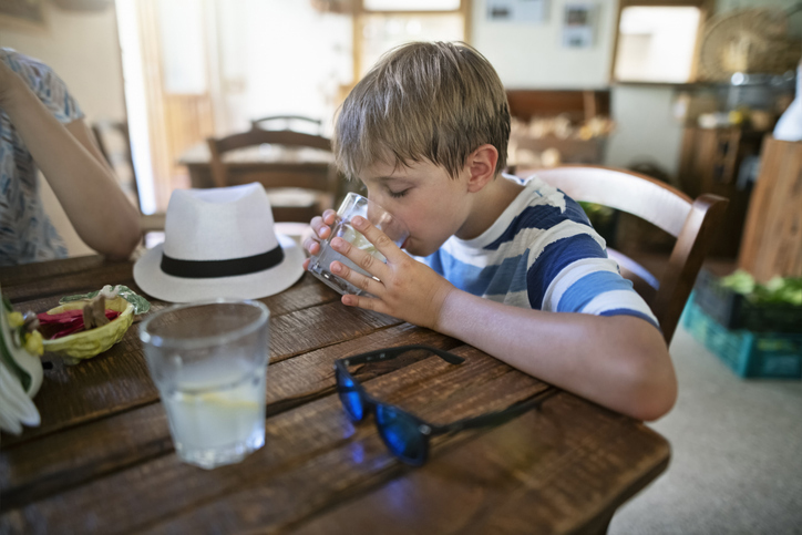 pre-teen out at a restaurant drinking water from a glass