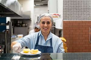 Female restaurant worker putting food on the counter for a server to pick up