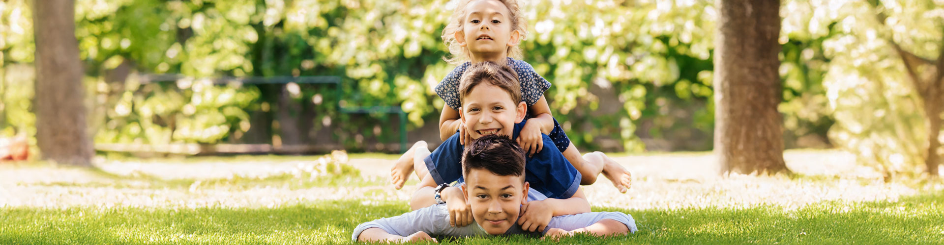 Kids joyfully piling on top of each other on the ground.