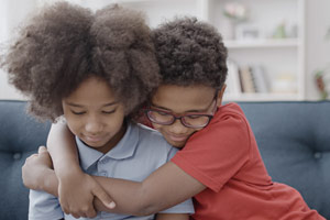 Two children embracing each other and smiling.