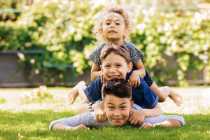 Kids joyfully piling on top of each other on the ground.