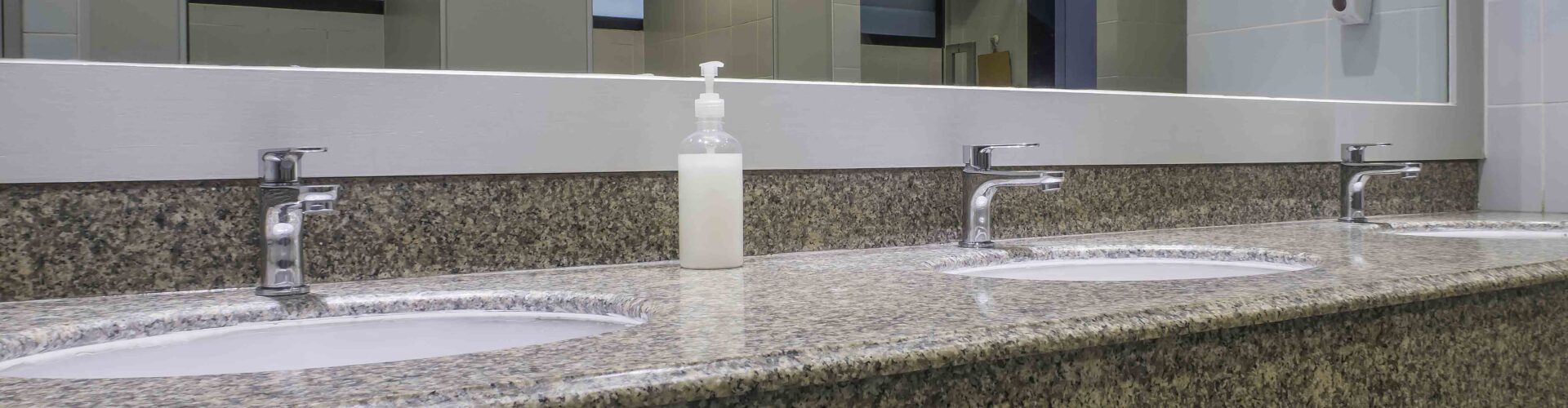 faucets with washbasin on granite counter in men restroom