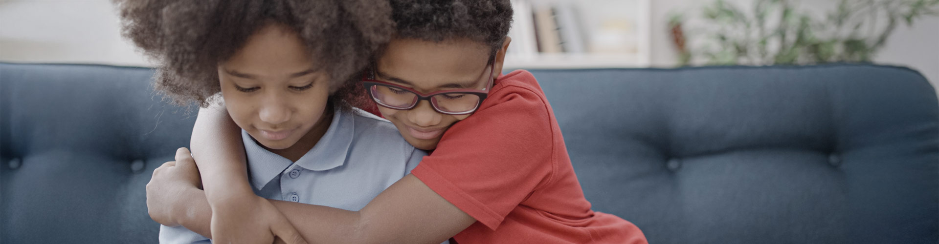 Two children embracing each other and smiling.