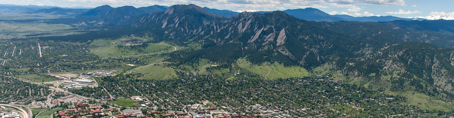 Aerial view of Boulder Colorado including the Flatiron's, housing and other buildings in summer when everything is green.
