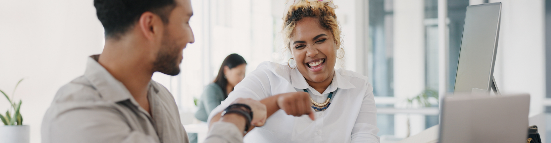 Two diverse co-workers, a man and a woman, smiling and giving each other a fist bump.