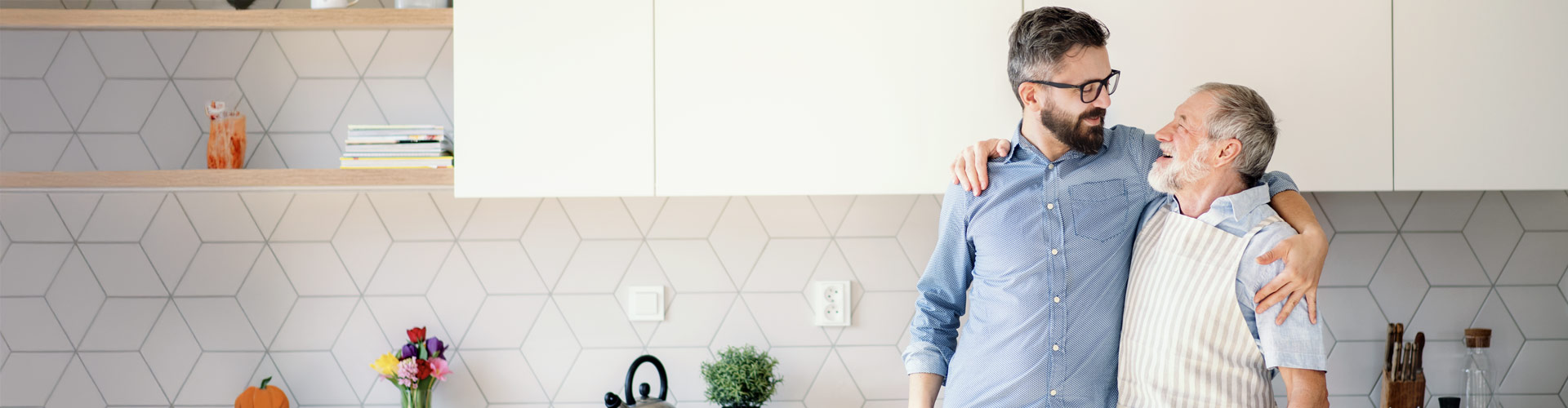 A father and son hugging, smiling, and looking at each other.
