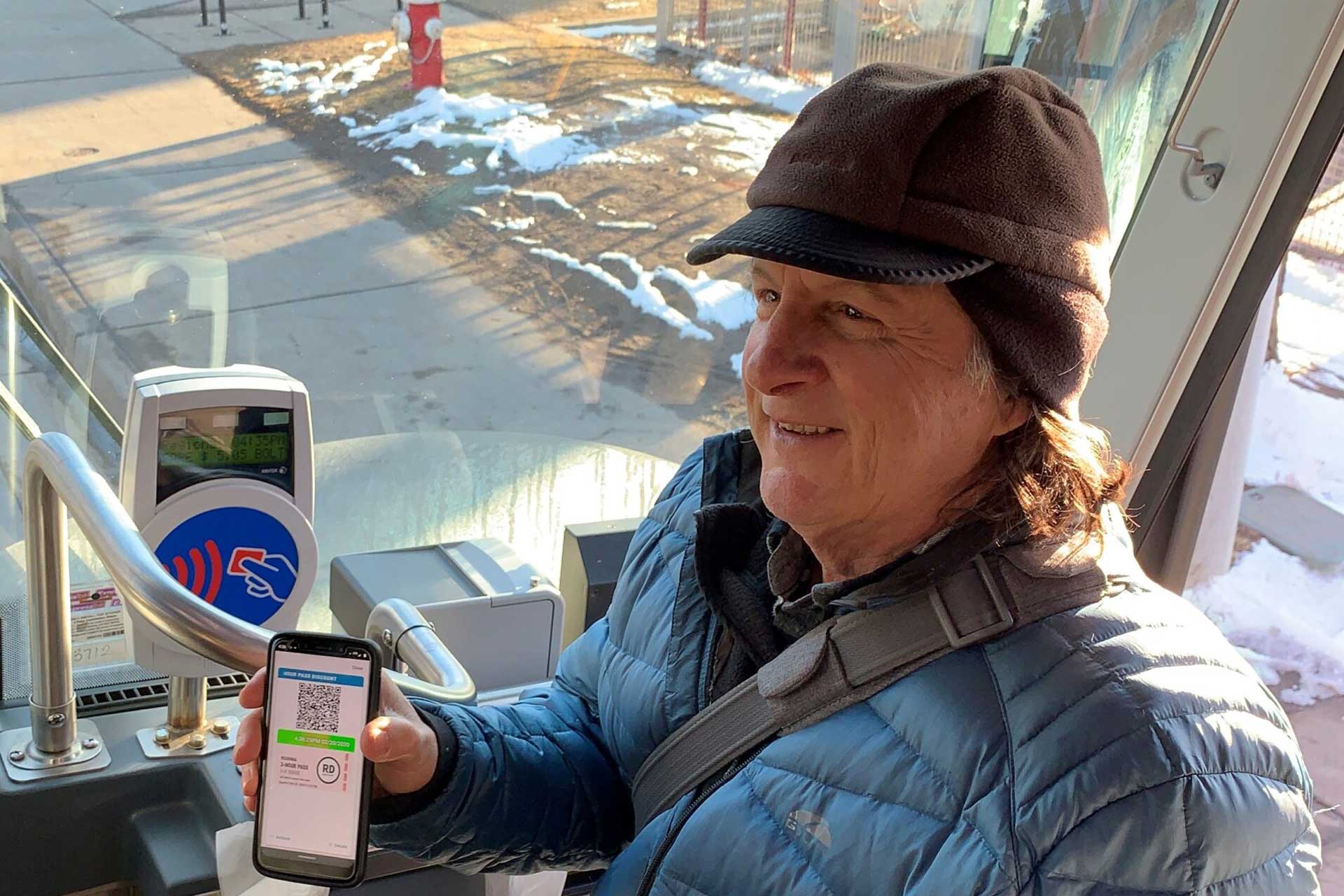 Adult boarding a bus and using their Ecopass from a phone.
