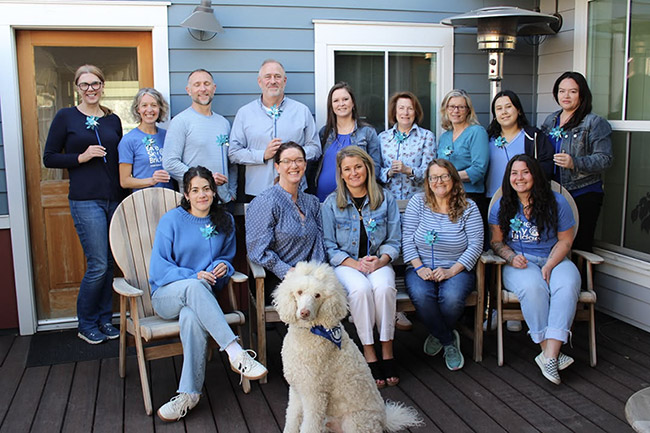 blue-sky-bridge-teams-family-portrait A family portrait of a blue sky bridge team standing together, with a therapy dog at their feet.