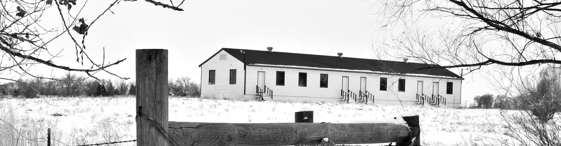 Black and white image taken on a snowy day of Las Barracas, a 1923 former military barrack repurposed as farmworker housing in Boulder County.