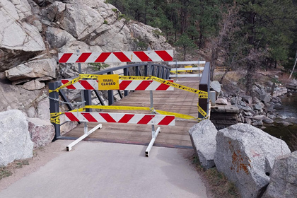 Barricades block a bridge with a sign that says Trail Closed