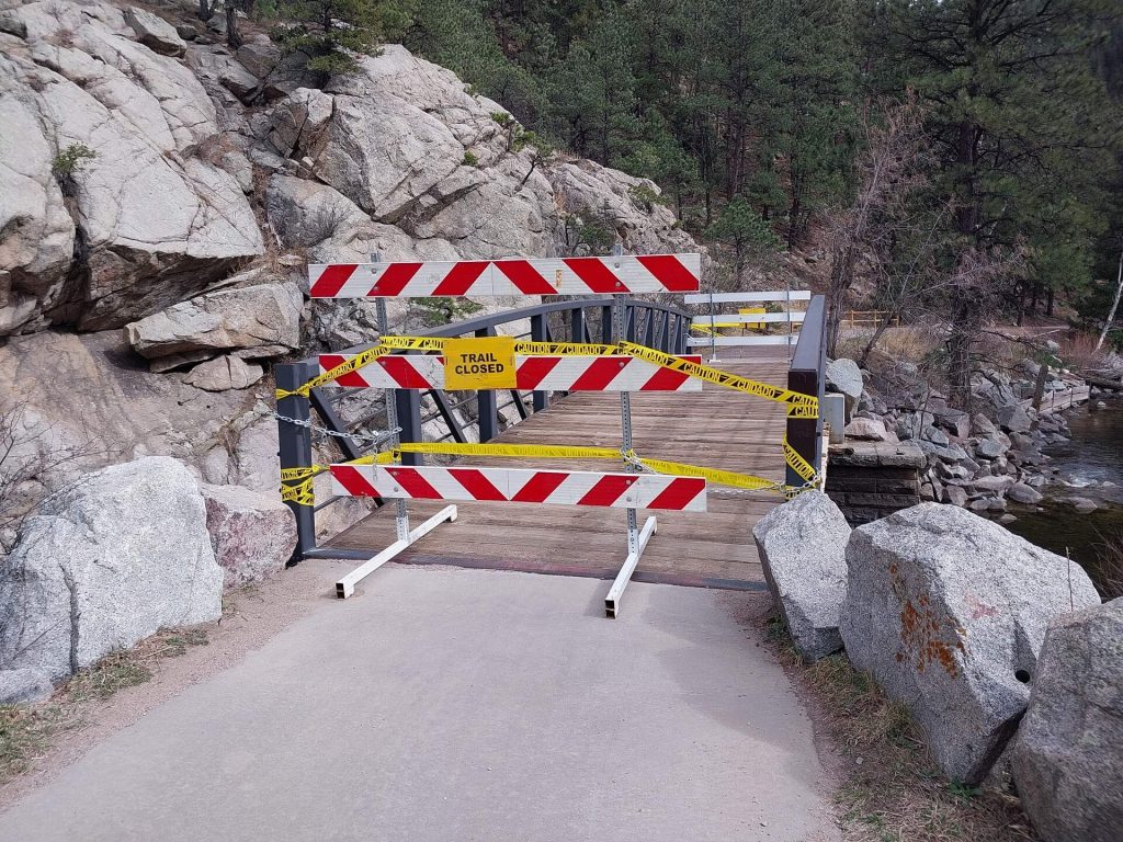 Barricades block a bridge with a sign that says Trail Closed