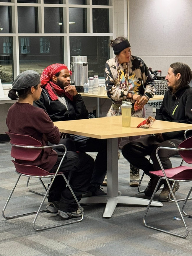 Four people sitting together in a small circle, participating in a mentoring support group session.