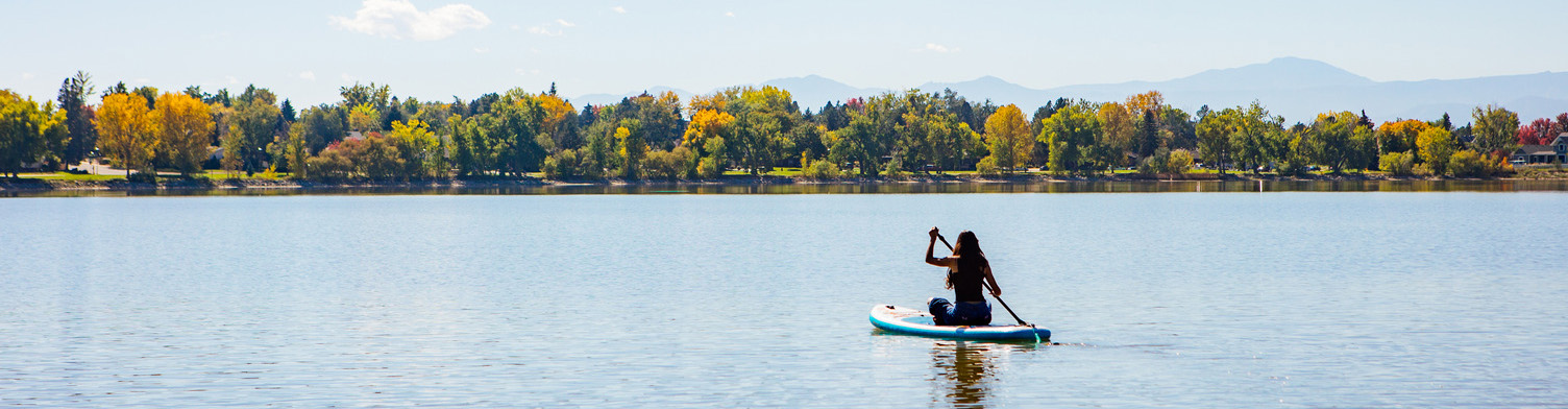 woman on a paddleboard on a lake with mountains in the background