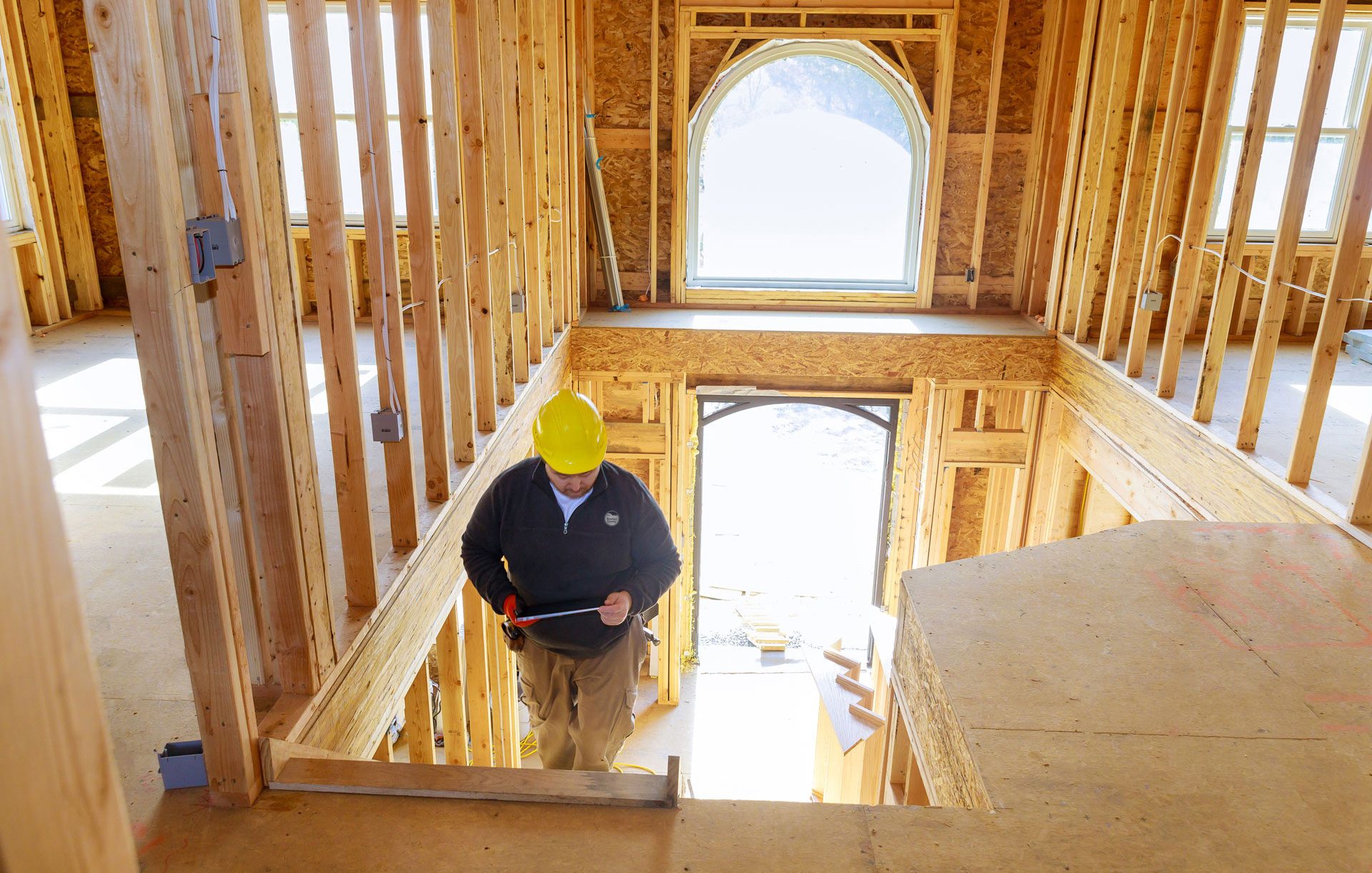 House under construction with an inspector walking up the indoor stairs.